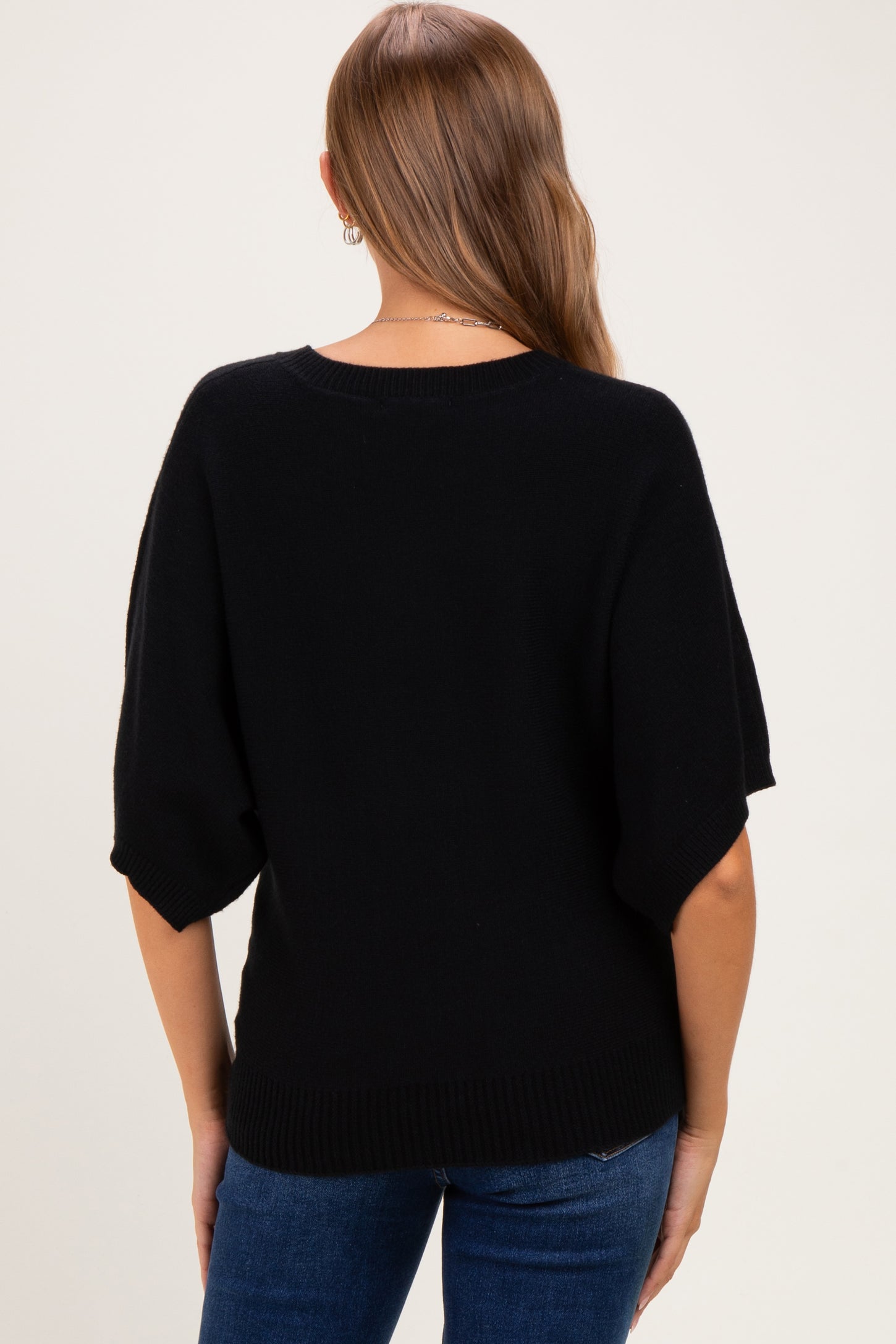 woman wearing a black maternity sweater with short sleeves, viewed from the back