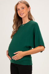 woman wearing a green short sleeve maternity sweater and holding her baby bump