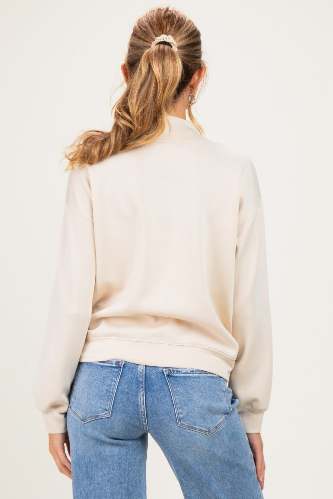 woman wearing a cream maternity sweatshirt with a relaxed fit and ribbed cuffs, seen from the back