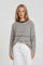 woman wearing a striped cream and black oversized sweater with a relaxed fit and long sleeves, paired with white pants