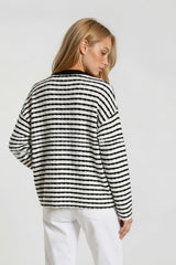woman wearing a black and white striped sweater with a relaxed fit, view of the back with long sleeves and a round neckline