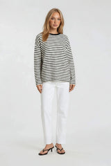 woman wearing a black and white striped sweater with long sleeves and white straight-leg pants