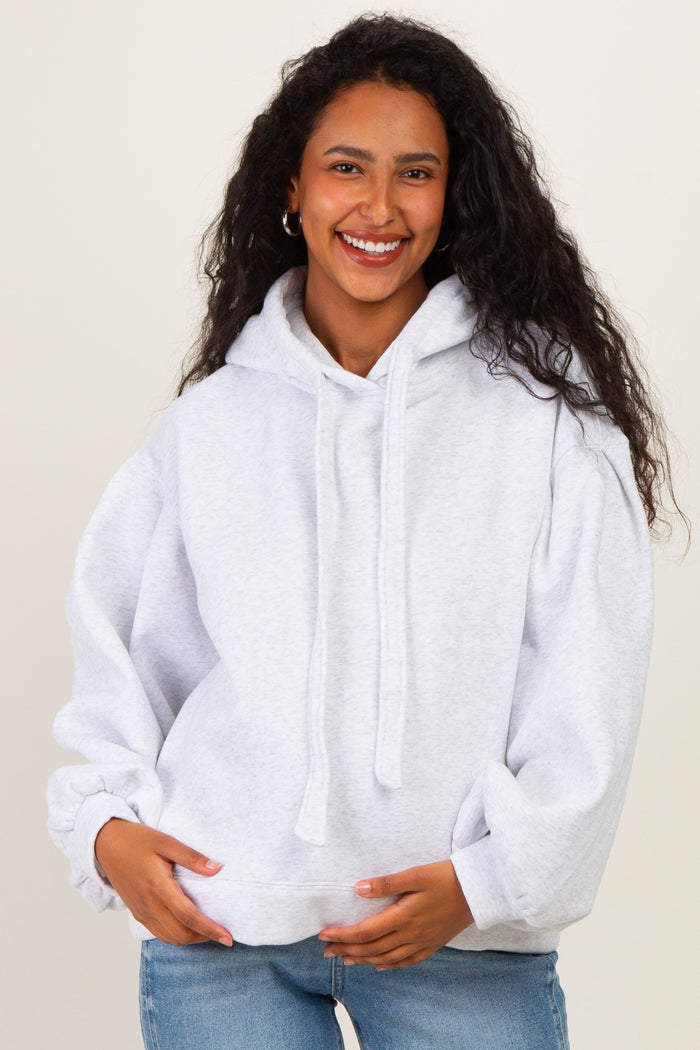 woman wearing a light grey maternity hoodie with a relaxed fit and holding her baby bump