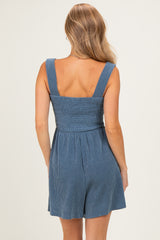 woman wearing a back view of a blue striped sleeveless romper with a smocked bodice and relaxed fit shorts