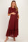 woman wearing a burgundy floral maternity dress with a ruffled hem and short sleeves, holding her baby bump
