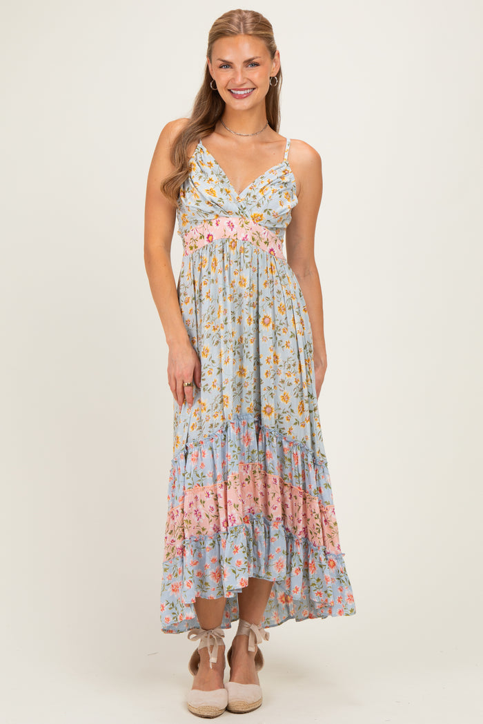 woman wearing a light blue floral maxi dress with adjustable straps and tiered ruffles at the hem