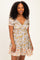 woman wearing a floral print short sleeve dress with a v-neck and ruffled hem in light colors