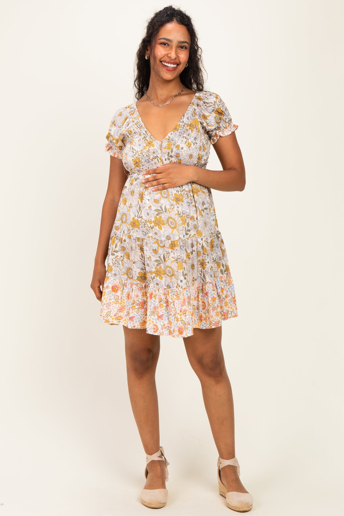 woman wearing a floral print maternity dress with short puff sleeves and a fitted waist, showing her baby bump