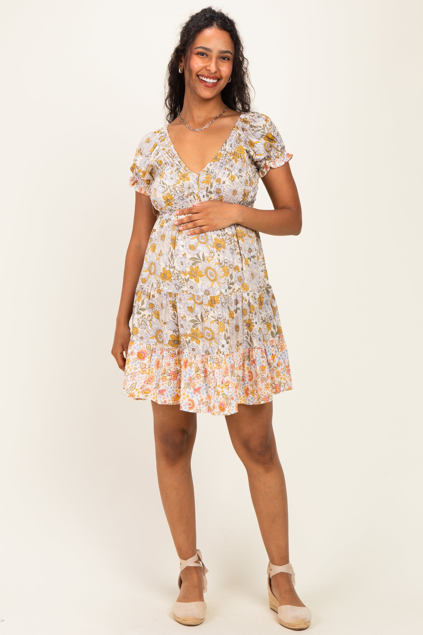 woman wearing a floral print maternity dress with short puff sleeves and a fitted waist, showing her baby bump