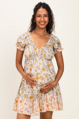 woman wearing a floral print maternity dress with short puff sleeves and a gathered waist, holding her baby bump