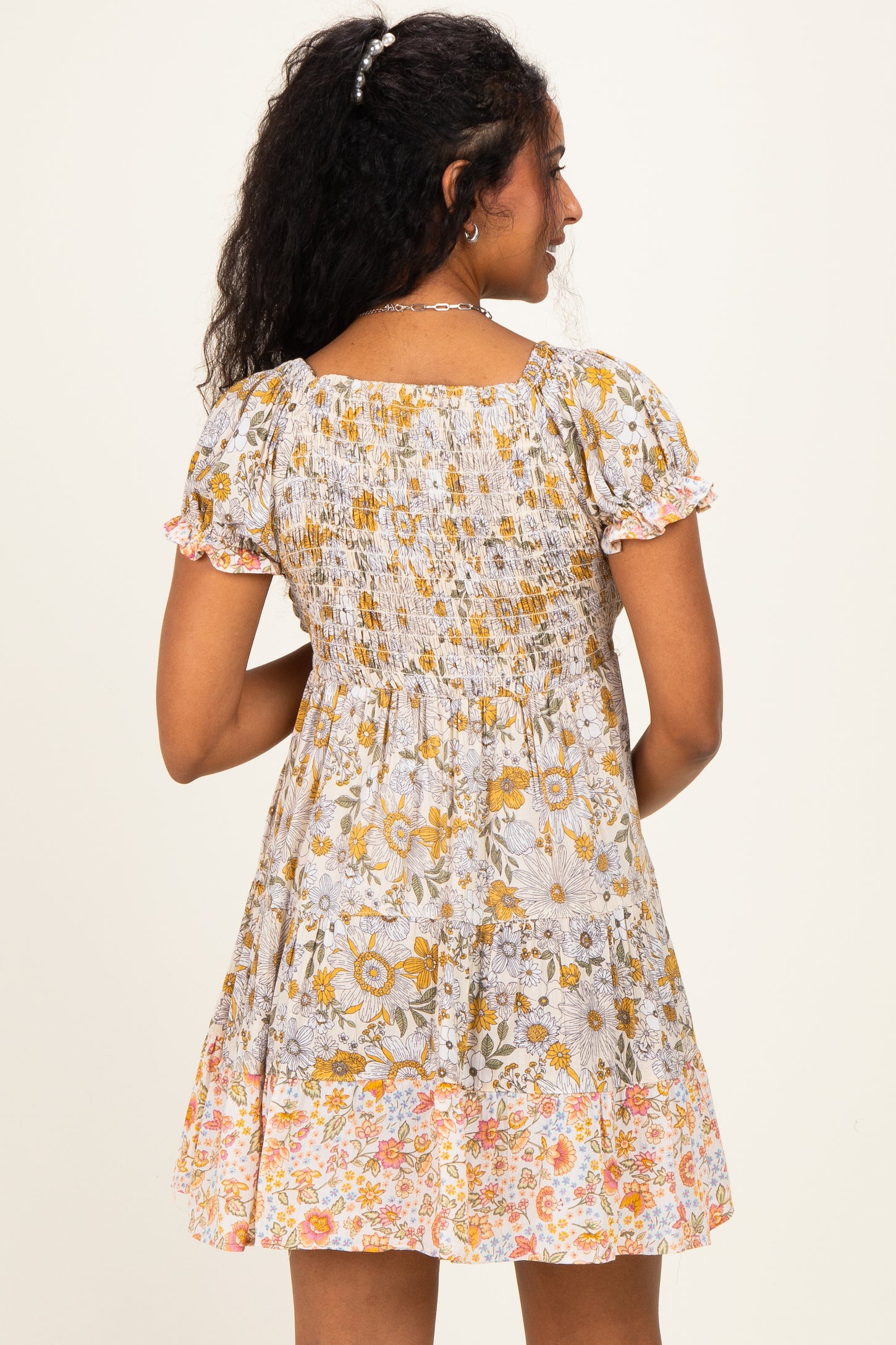 woman wearing a floral print maternity dress with short puff sleeves and a smocked bodice, showing a baby bump