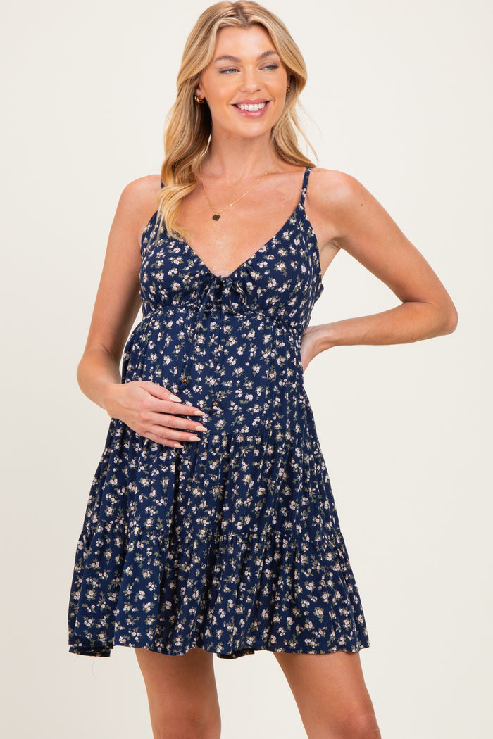 woman wearing a navy blue floral maternity dress and gently cradling her baby bump