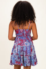 woman wearing a patterned blue and red summer dress with a fitted bodice and flared skirt, shown from the back