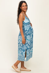 woman wearing a blue floral maternity maxi dress with side slits and holding her baby bump