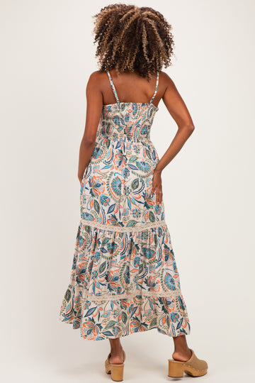woman wearing a floral print maternity maxi dress with smocked bodice and tiered skirt, showing her back