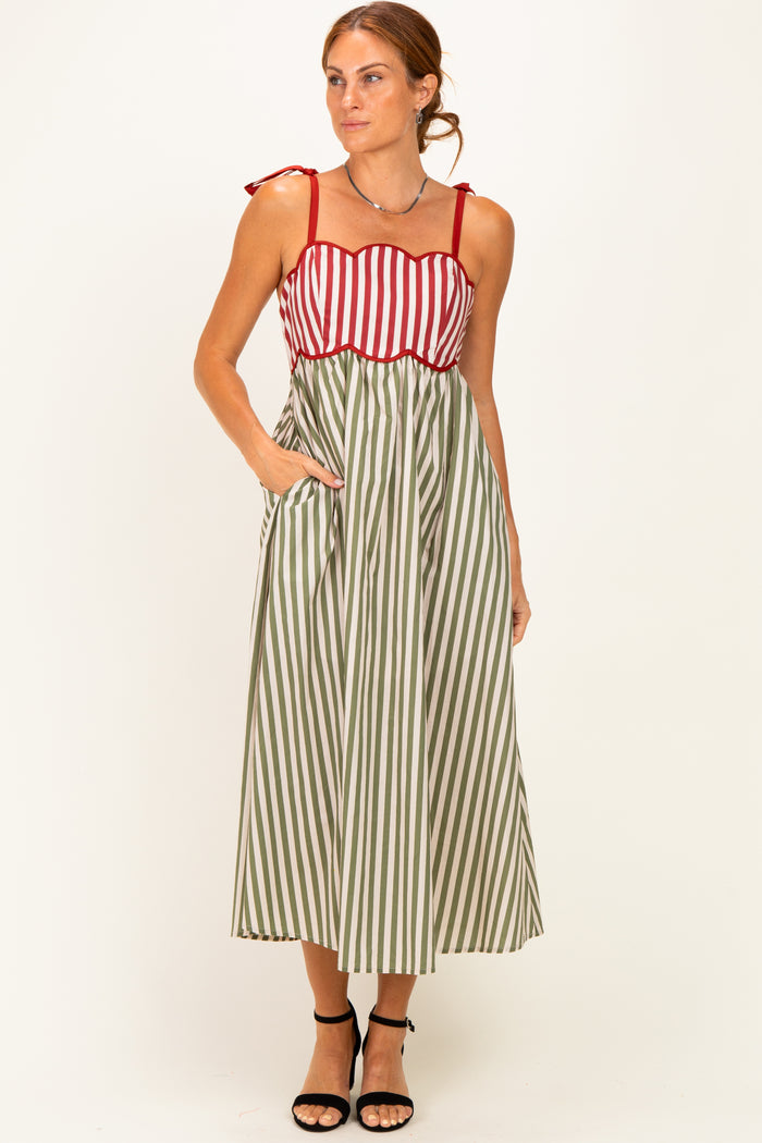woman wearing a red and white striped maxi dress with green stripes, featuring tie straps and pockets