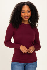 woman wearing a maroon long sleeve top with a scoop neckline and styled hair