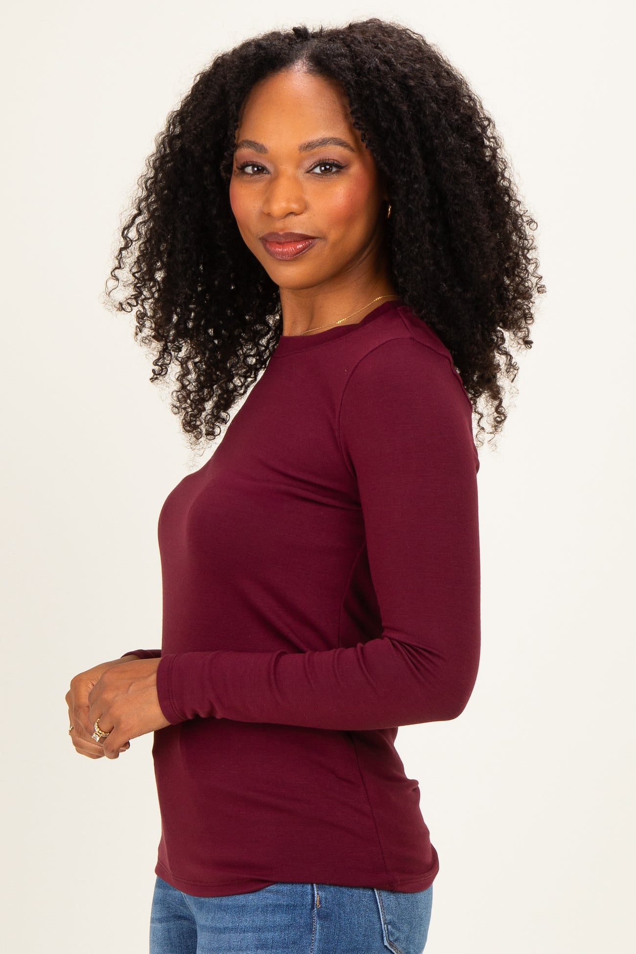 woman wearing a burgundy long sleeve top with a fitted style and round neckline