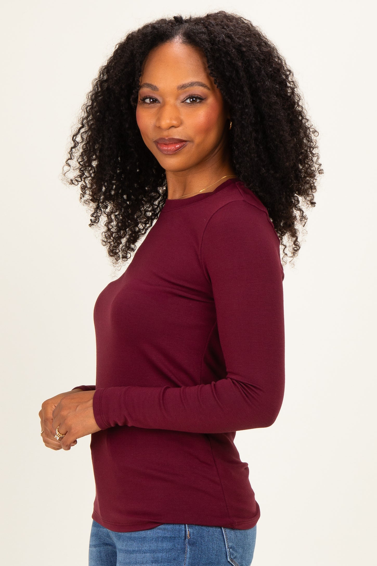 woman wearing a burgundy long sleeve top with a fitted style and round neckline