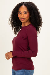 woman wearing a burgundy long sleeve top with a fitted style and round neckline