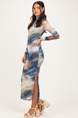 woman wearing a long sleeve printed maxi dress with side slits and a high neck in blue and brown tones