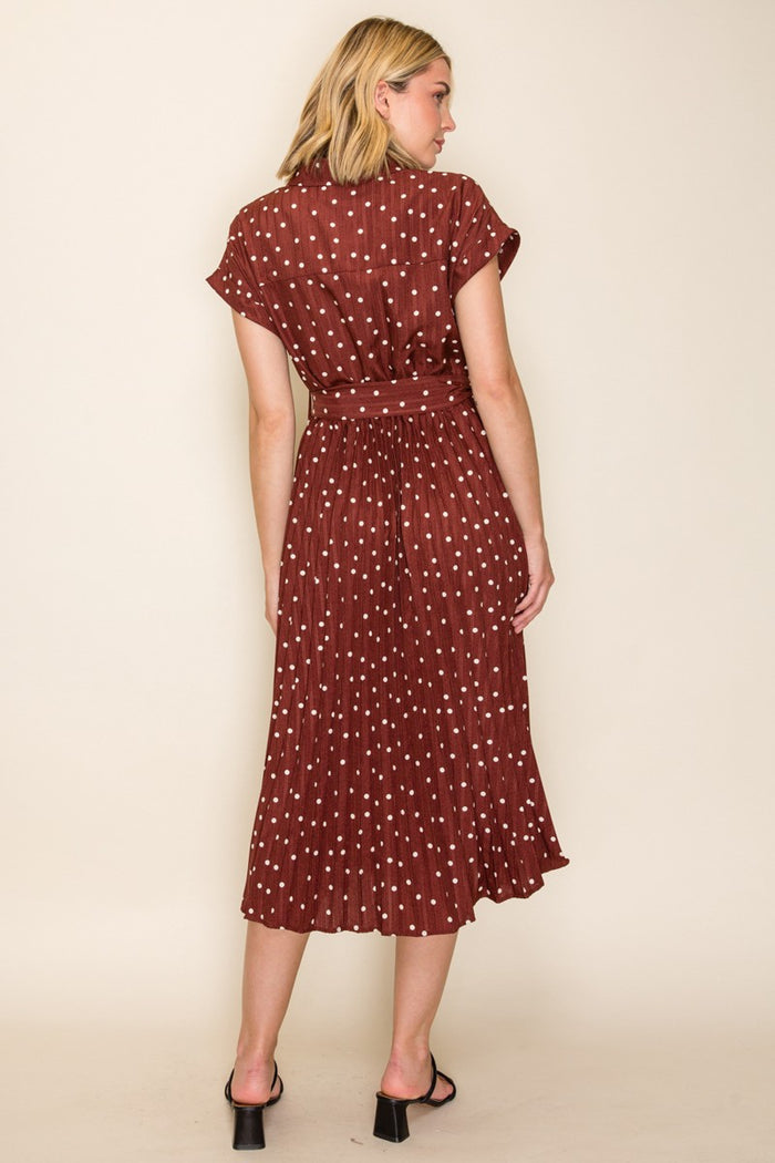 woman wearing a maroon polka dot midi dress with short sleeves and a cinched waist, shown from the back