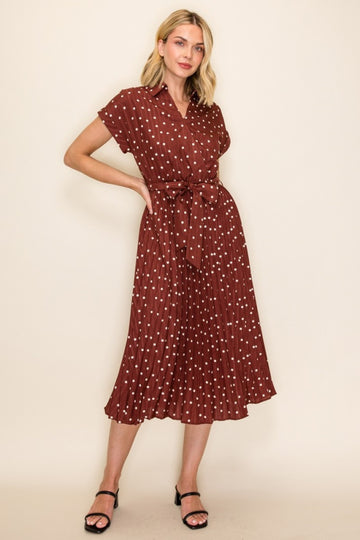woman wearing a burgundy short sleeve collared dress with white polka dots and a tie belt, model standing in a relaxed pose
