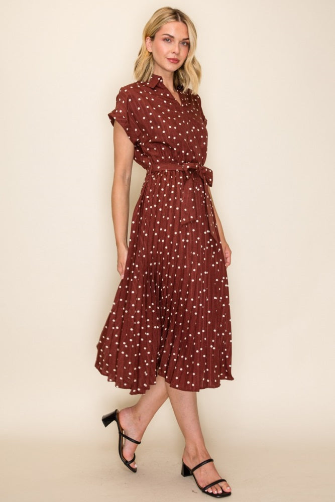 woman wearing a maroon short sleeve shirt dress with white polka dots and a tie waist detail, styled with black sandals