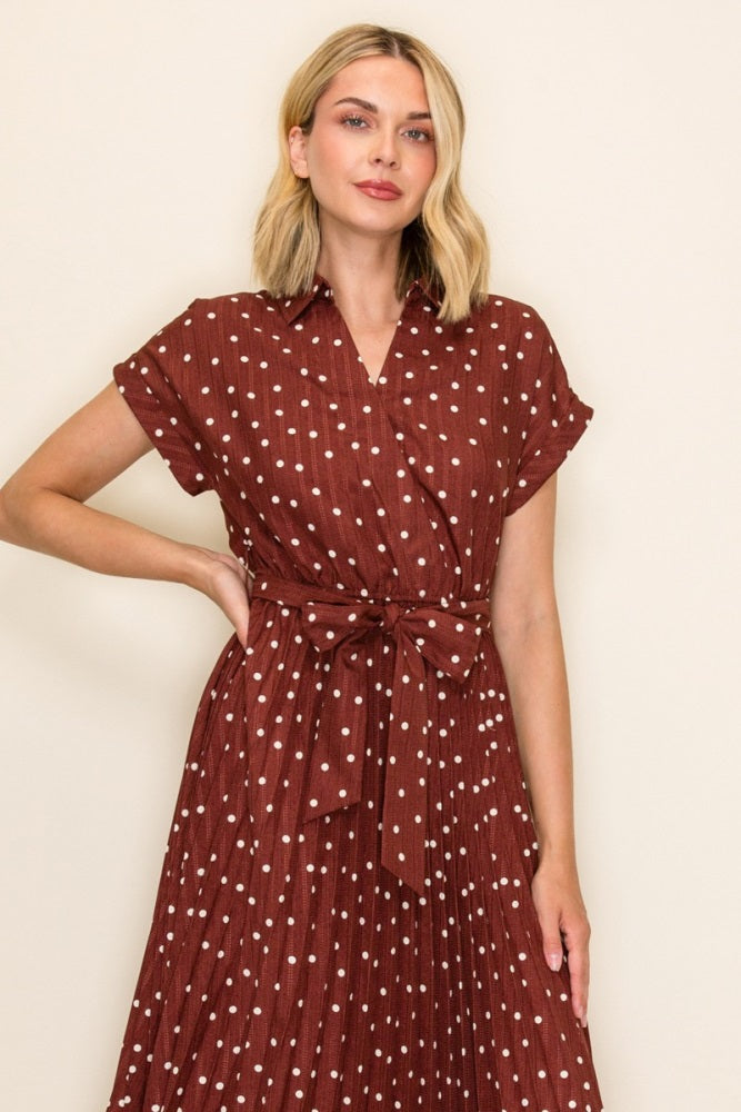 woman wearing a rust-colored short sleeve dress with white polka dots and a tied waist detail