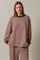 woman wearing a brown and pink striped oversized sweatshirt with long sleeves and a round neckline