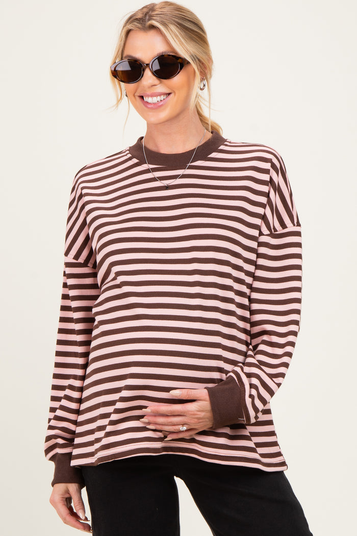 woman wearing a brown and pink striped maternity top with a visible baby bump and sunglasses
