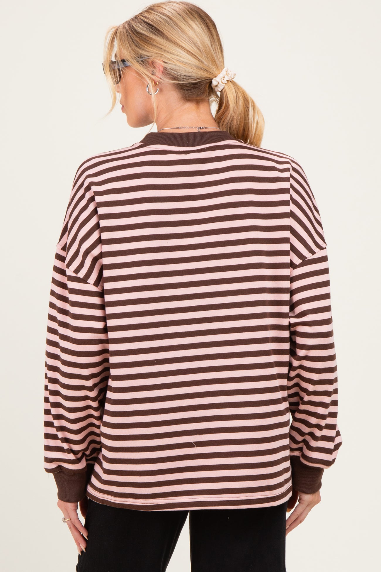 woman wearing a brown and light pink striped maternity sweatshirt, view from the back, with a ponytail hairstyle
