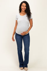 woman wearing a gray short sleeve maternity top and blue flared jeans, showing her baby bump