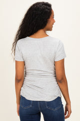 woman wearing a light gray short sleeve maternity top with gathered side details, showing her back