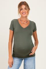 woman wearing a green short sleeve maternity top with ruching and showing her baby bump