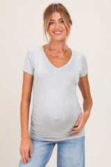 woman wearing a light gray short sleeve maternity top with a v-neck and a visible baby bump