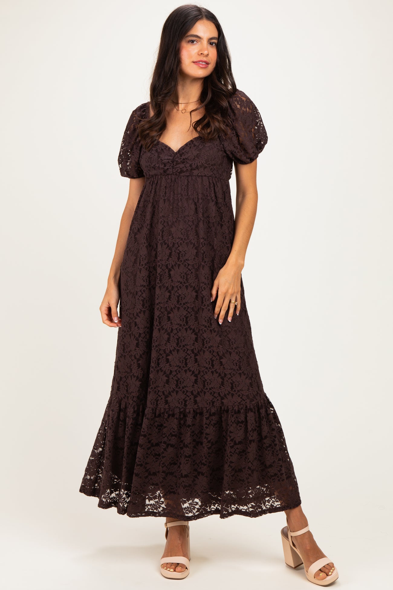 woman wearing a dark brown lace maxi dress with puff sleeves and a tiered hem