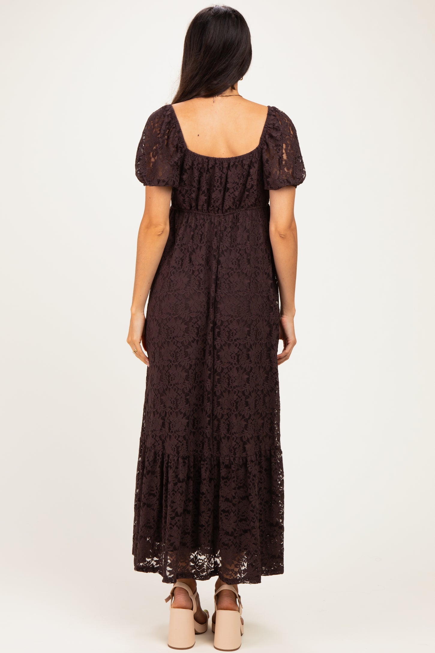 woman wearing a dark brown lace maxi dress with puff sleeves and a tiered skirt, shown from the back