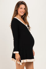 woman wearing a black ribbed maternity dress with a v-neck and ruffle hem, showing her baby bump