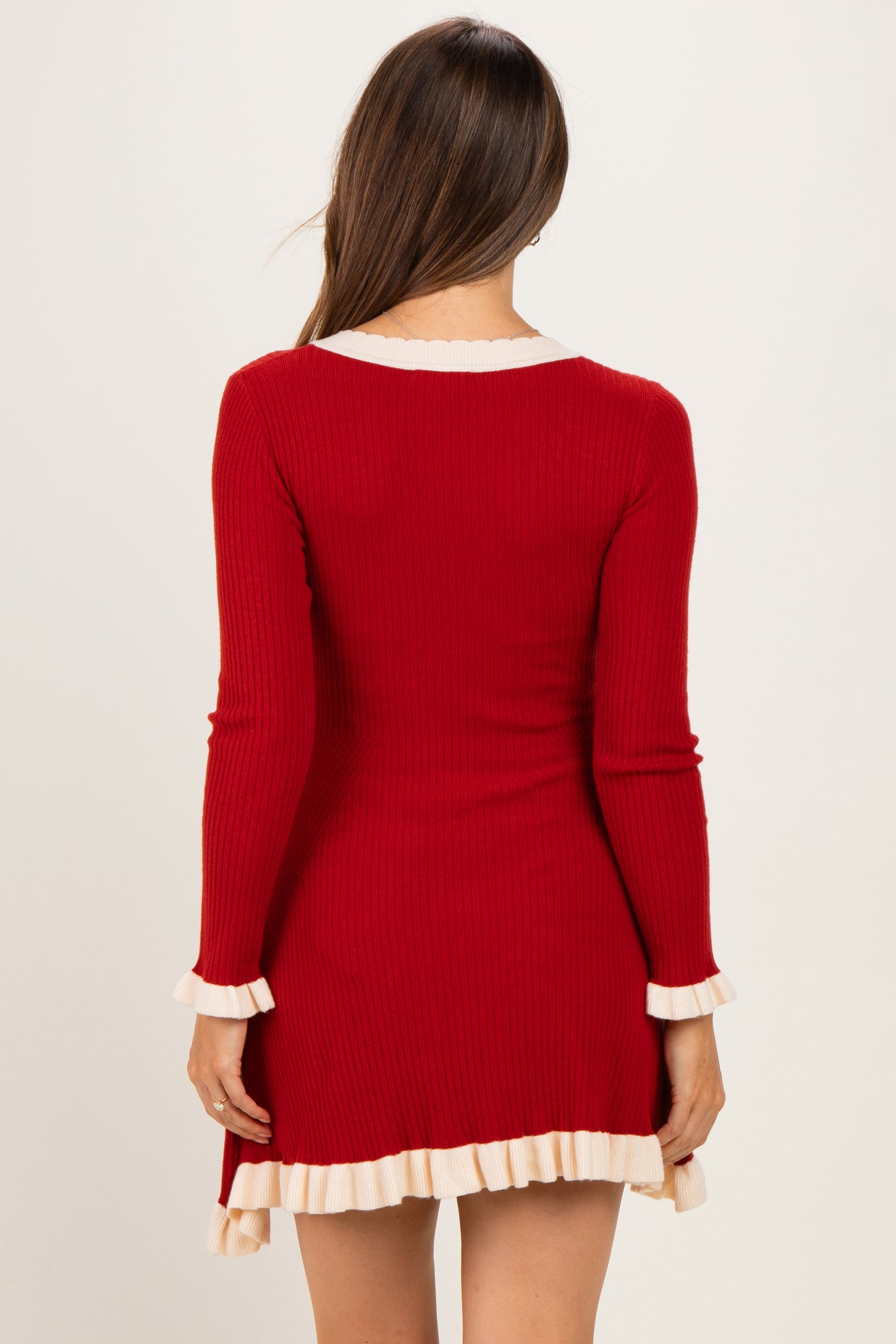 woman wearing a red ribbed maternity dress with cream ruffle trim and long sleeves