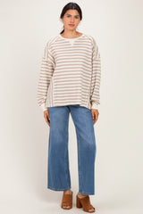 woman wearing a cream and beige striped oversized sweater with wide leg blue jeans and tan heeled sandals