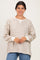 woman wearing a cream and beige striped oversized sweatshirt with a crew neckline and long sleeves