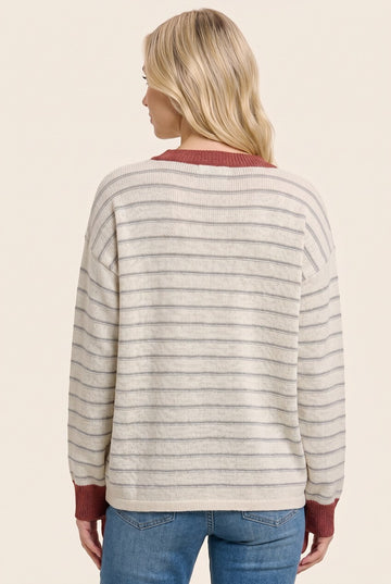 woman wearing a cream and gray striped sweater with a maroon collar, viewed from the back, paired with blue jeans
