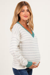 woman wearing a striped maternity sweater with a teal v-neck and holding her baby bump