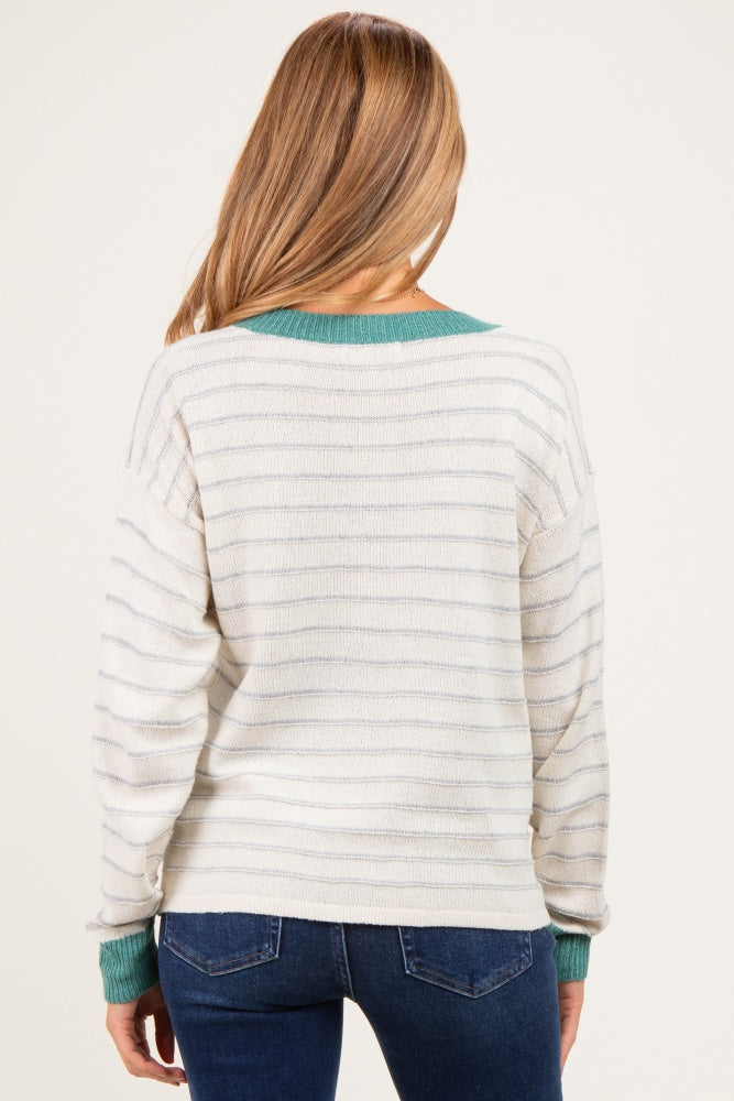 woman wearing a cream and gray striped maternity sweater with a teal accent at the collar and cuffs, seen from the back