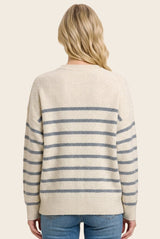 woman wearing a cream oversized sweater with blue stripes, view from the back, paired with light blue jeans