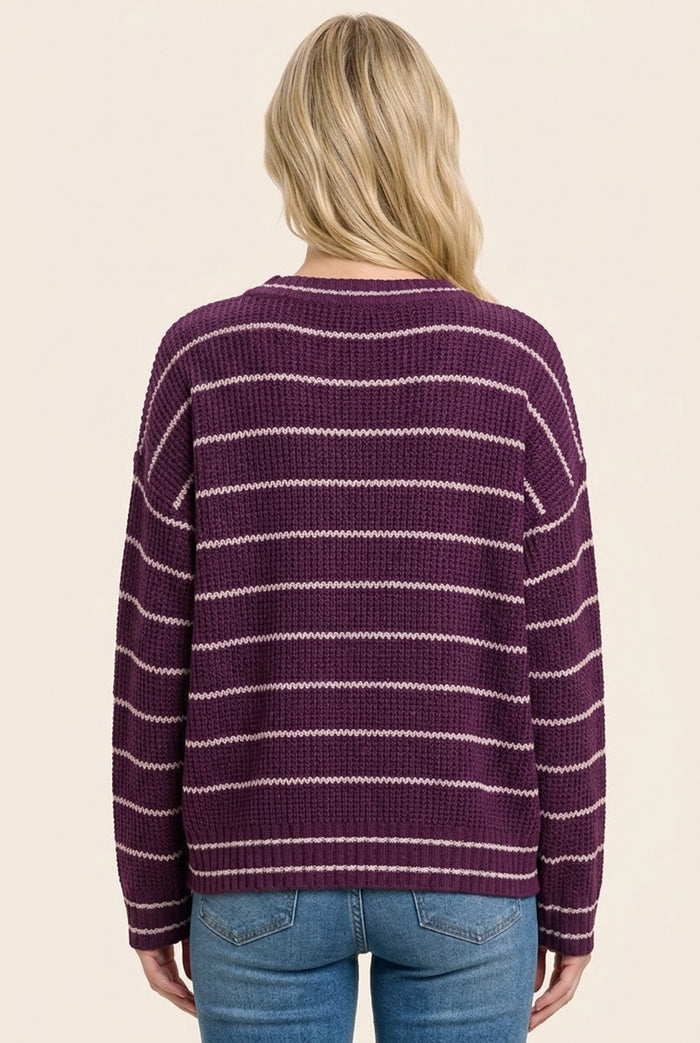 woman wearing a purple striped knit sweater and blue jeans, viewed from the back