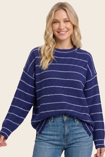 woman wearing a navy blue striped sweater with a relaxed fit and long sleeves, paired with light denim jeans