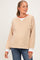 woman wearing a striped maternity sweatshirt in beige and white with red accents, styled with jeans and a baby bump visible