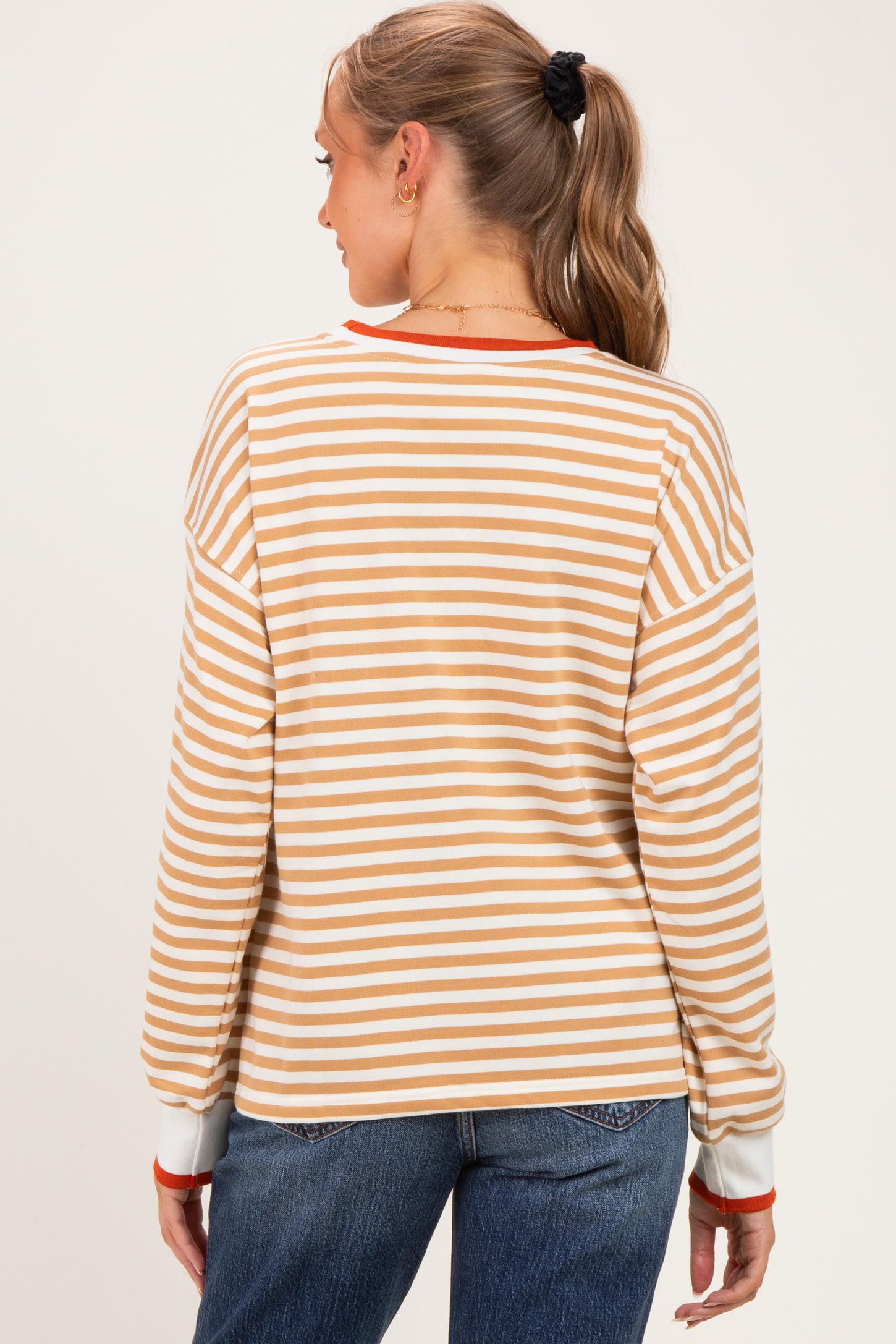 woman wearing a striped maternity sweatshirt in peach and white, with long sleeves and a relaxed fit